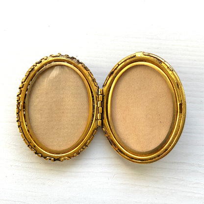 A gold-tone locket brooch featuring a floral motif accented with turquoise blue cabochons.  ゴールドトーンのお花に、ターコイズブルーのカボションが映えるロケットブローチ。