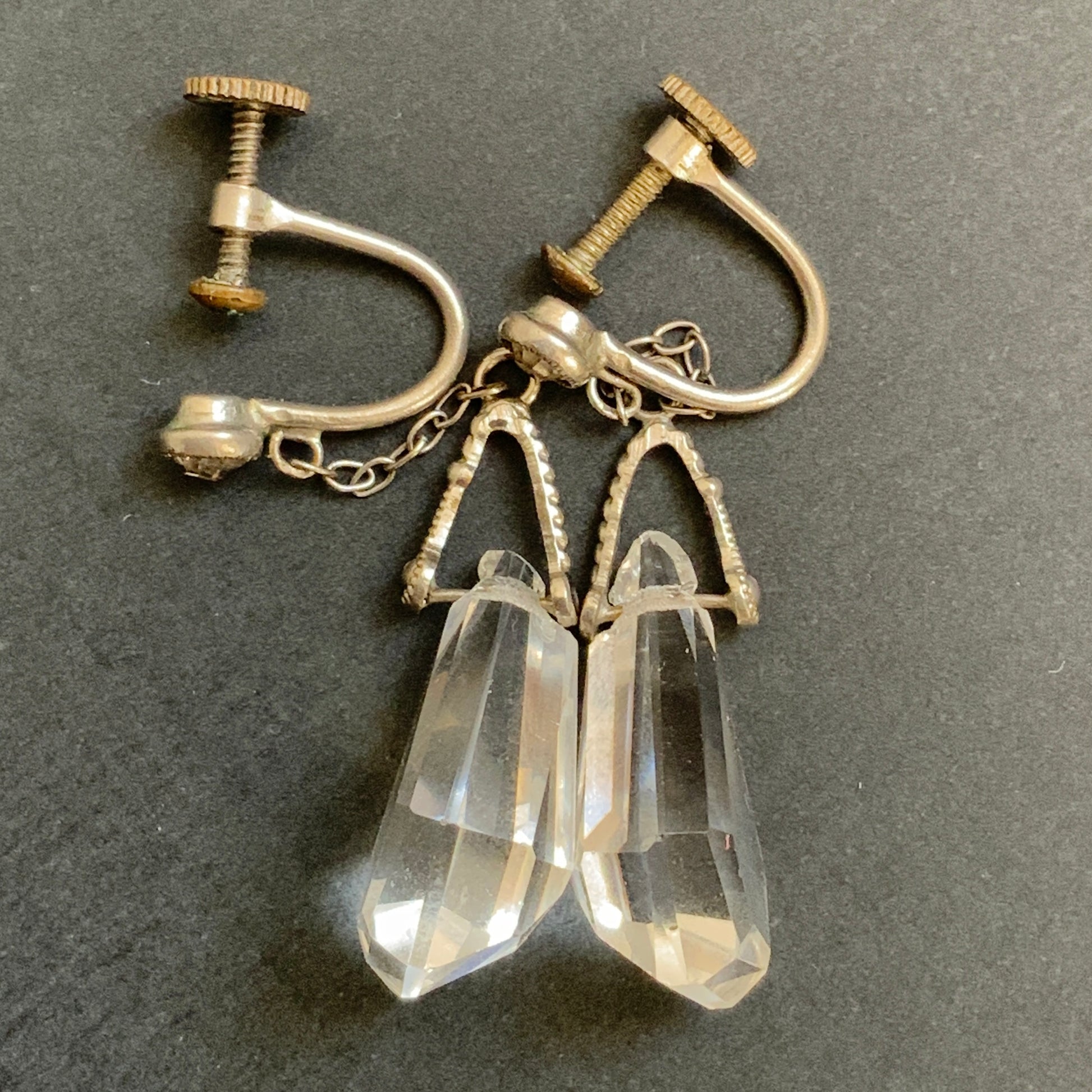 Screw-back earrings featuring clear faceted glass in a unique triangular form. ユニークな三角フォルムのファセットグラスが揺れる、スクリューイヤリング。