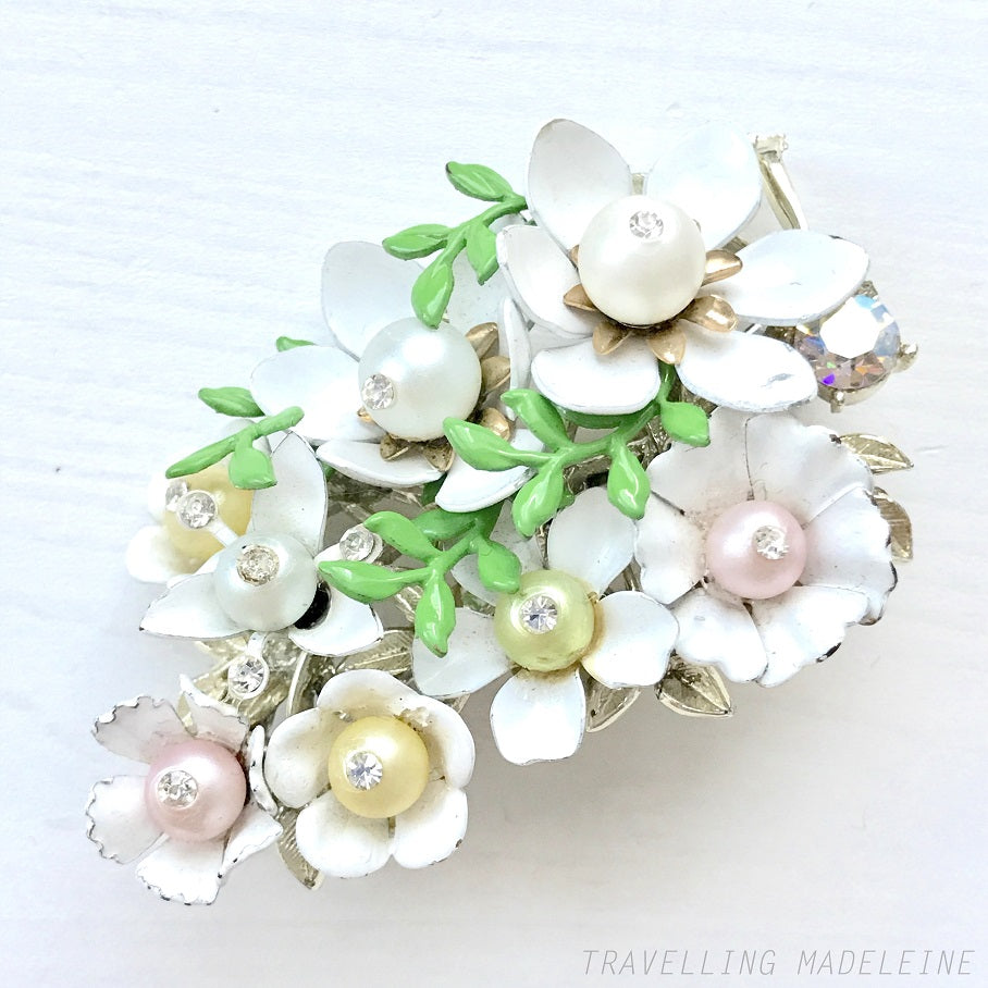 Vintage 1950s brooch featuring white enamel flowers adorned with soft pastel-coloured pearls. ホワイトエナメルの花に淡いパステルカラーのパールがあしらわれた、1950年代のヴィンテージブローチ。