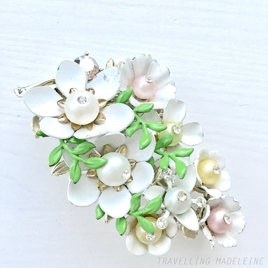 Vintage 1950s brooch featuring white enamel flowers adorned with soft pastel-coloured pearls. ホワイトエナメルの花に淡いパステルカラーのパールがあしらわれた、1950年代のヴィンテージブローチ。