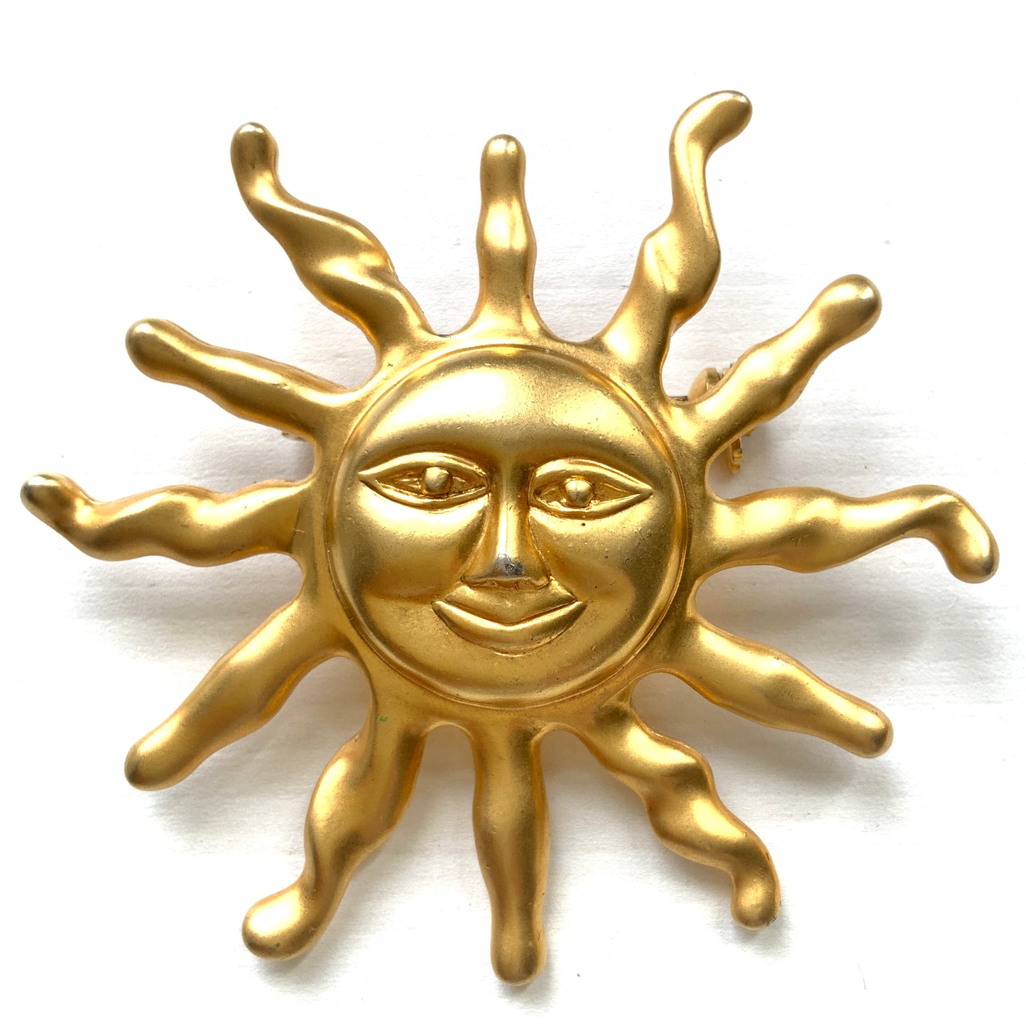 A charming vintage sun brooch featuring a smiling golden face. 微笑みをたたえたゴールドトーンの太陽が印象的なヴィンテージブローチ。