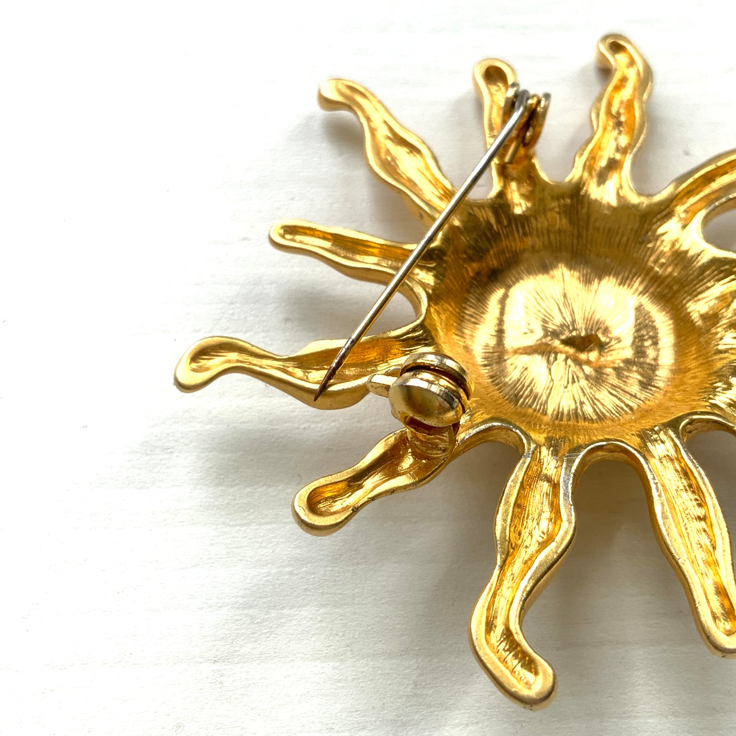 A charming vintage sun brooch featuring a smiling golden face. 微笑みをたたえたゴールドトーンの太陽が印象的なヴィンテージブローチ。