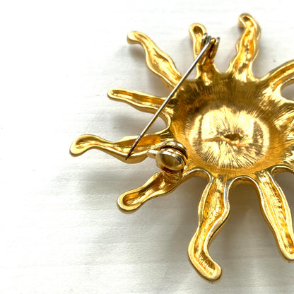 A charming vintage sun brooch featuring a smiling golden face. 微笑みをたたえたゴールドトーンの太陽が印象的なヴィンテージブローチ。