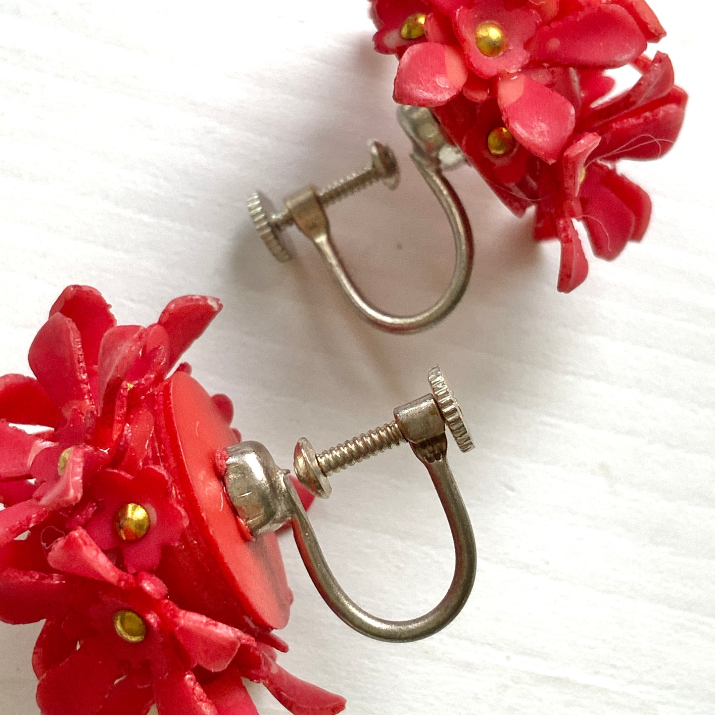 A charming pair of 1960s screw back earrings from Czechoslovakia, featuring vibrant red plastic flowers arranged in a beautiful three-dimensional cluster. 赤いお花の1960年代のチェコスロヴァキアのヴィンテージスクリューイヤリング。